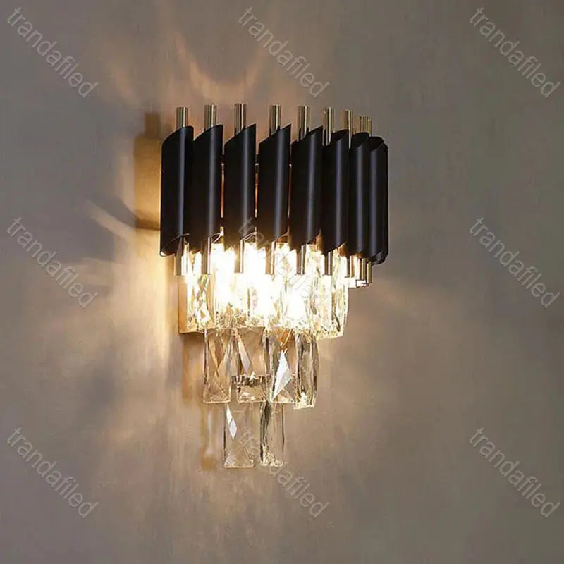 black-and-gold-wall-sconce-with-clear-crystal-pendants-turned-on-mounted-on-wall-elegant-modern-indoor-lighting